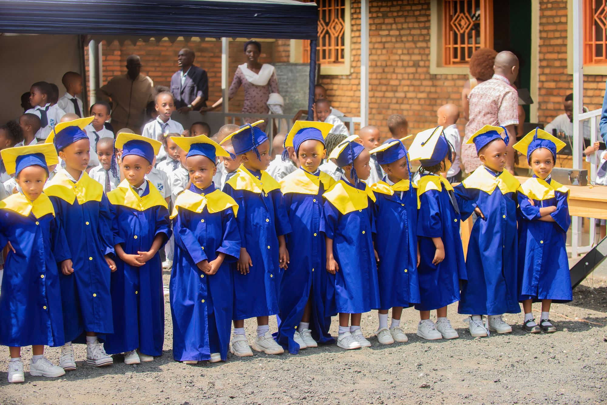 Top Class pupils in blue and gold graduation gowns lined up in the school yard on graduation day