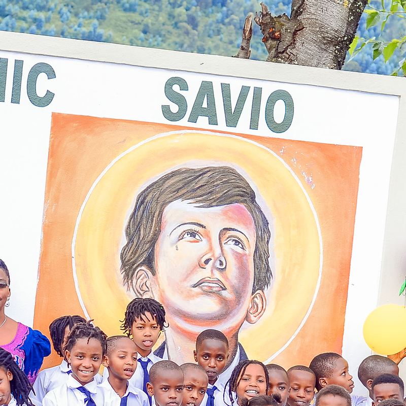 The painted mural of St Dominic Savio on the school wall, with pupils below