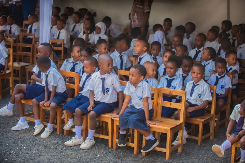 Primary pupils in white shirts and navy ties seated in rows at a school event