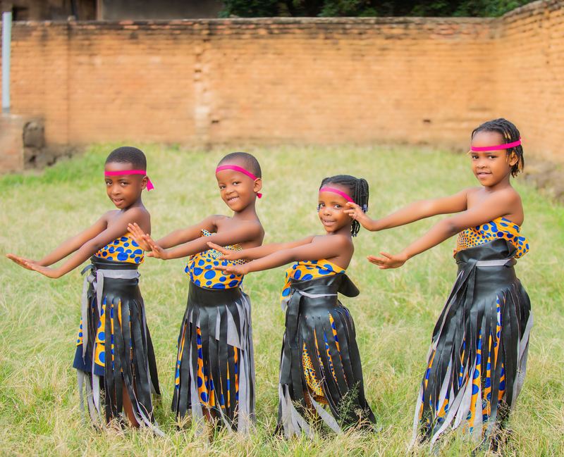 Four young pupils in traditional dance costume performing on the grass